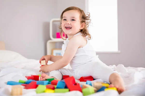 Nettes Mädchen spielt mit Bausteinen auf dem Bett — Stockfoto