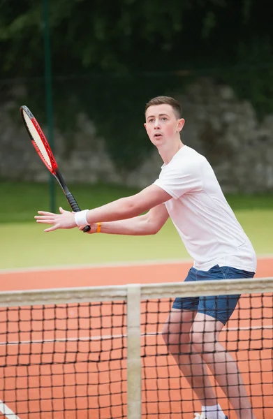 Jeune joueur de tennis frappant balle — Photo