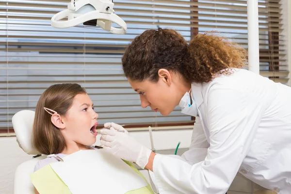 Детский дантист осматривает зубы маленьких девочек — стоковое фото