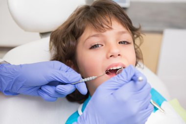 Pediatric dentist examining a little boys teeth in the dentists  clipart