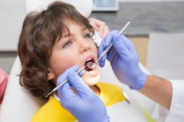 Dentist examining boys teeth clipart