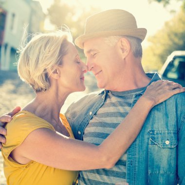 Happy mature couple smiling at each other in the city clipart