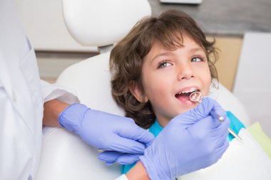 Pediatric dentist examining a little boys teeth in the dentists  clipart