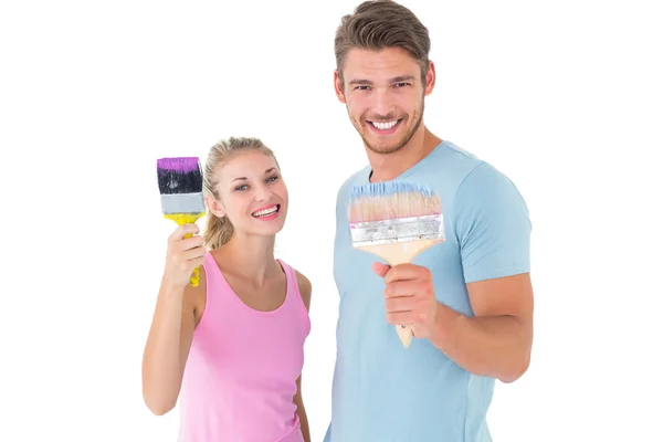 Jovem casal sorrindo e segurando pincéis — Fotografia de Stock