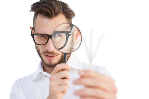 Nerdy businessman looking through magnifying glass — Stock Photo, Image