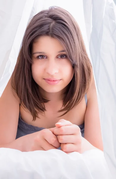 Linda morena sorrindo para a câmera na cama — Fotografia de Stock