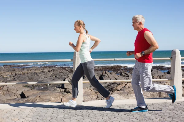 Ajuste pareja madura corriendo juntos en el muelle —  Fotos de Stock