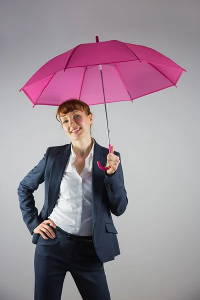 Smiling businesswoman holding pink umbrella — Stock Photo, Image
