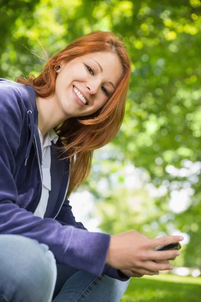 Redhead relaxing in the park sending a text — Stock Photo, Image