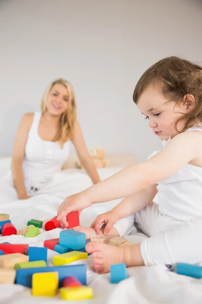 母亲和女儿玩积木在床上 — 图库照片