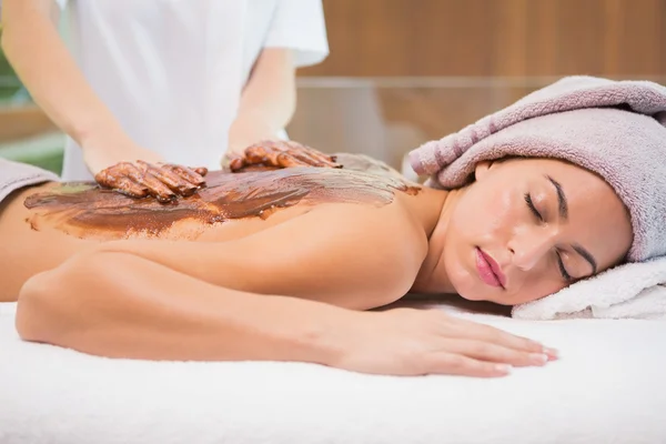 Attractive woman receiving chocolate back mask at spa center — Stock Photo, Image