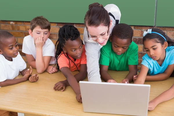 Учитель и ученики, работающие за ноутбуком — стоковое фото