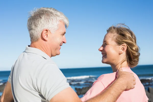 Happy casual couple smiling at each other by the coast — Stock Photo, Image