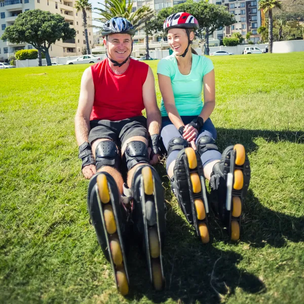 Fit mature couple wearing roller blades on the grass — Stock Photo, Image