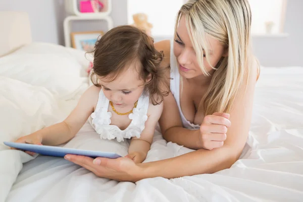 Mãe e filha usando tablet digital na cama — Fotografia de Stock