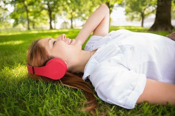 Redhead liggen op gras luisteren naar muziek — Stockfoto