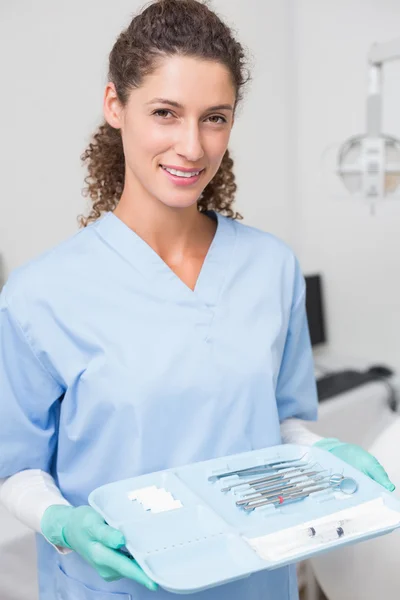 Dentista en matorrales azules sosteniendo bandeja de herramientas —  Fotos de Stock