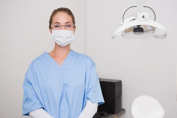 Стоматолог в синей форме смотрит на камеру в маске — стоковое фото