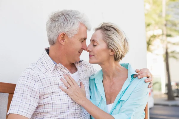 Happy mature couple sitting on bench in the city — Stock Photo, Image