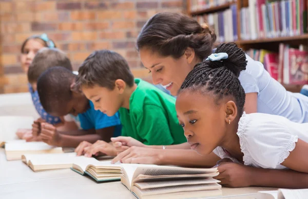 Leerlingen en leraar liggend op de vloer in bibliotheek — Stockfoto