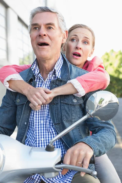 Happy senior couple riding a moped — Stock Photo, Image