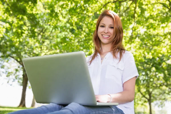 Redhead met haar laptop in het park — Stockfoto