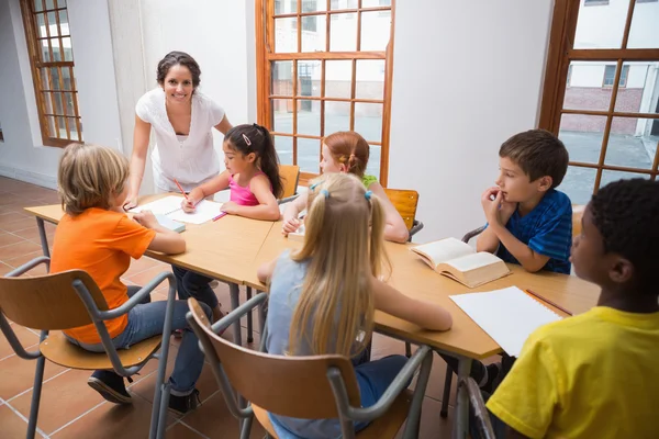 Teacher standing with pupils at desk — Stock Photo, Image