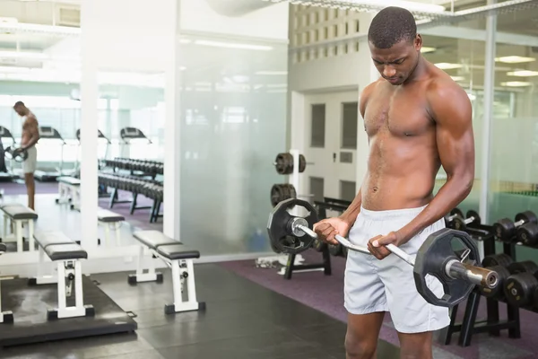 Shirtless man lifting barbell in gym — Stock Photo, Image