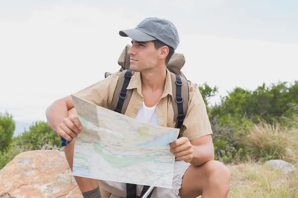 Turistika muž sedí s mapou na horském terénu — Stock fotografie