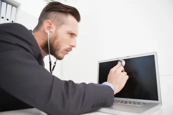 Affärsman som lyssnar på laptop med stetoskop — Stockfoto