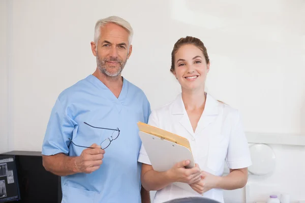 Стоматолог и ассистент улыбаются в камеру — стоковое фото