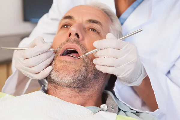 Dentista examinando los dientes de un paciente — Foto de Stock