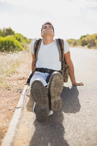 Hiking man sitting on countryside road — Stock Photo, Image