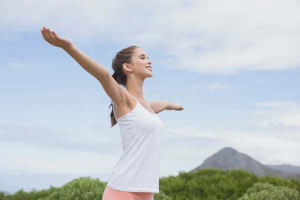 Mujer hermosa con los brazos levantados contra el cielo — Foto de Stock