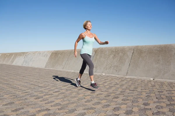 Aktive Seniorin joggt auf der Seebrücke — Stockfoto