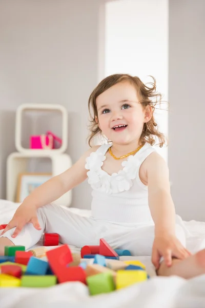 Leuk meisje spelen met bouwstenen op bed — Stockfoto