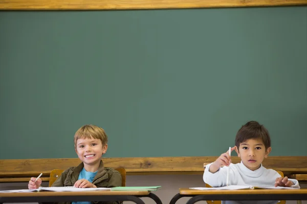 Pupils writing in notepad at desks — Stock Photo, Image