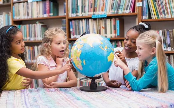 Ученики смотрят на глобус в библиотеке — стоковое фото