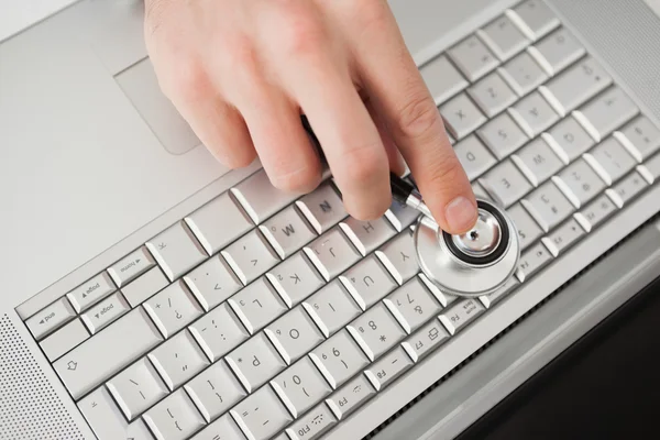 Technician listening to laptop with stethoscope — Stock Photo, Image