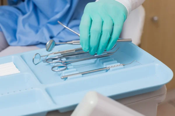 Dentista in scrub blu raccogliendo strumenti — Foto Stock