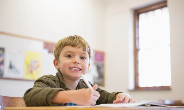 Pupil writing in notepad at his desk — Stock Photo, Image