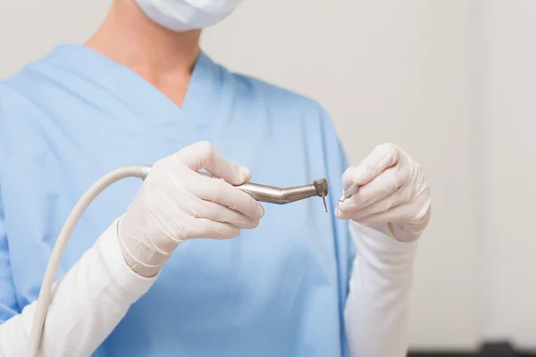 Dentist in blue scrubs holding drill — Stock Photo, Image