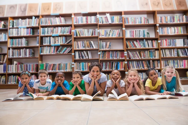 Elever och lärare liggande på golvet i biblioteket — Stockfoto