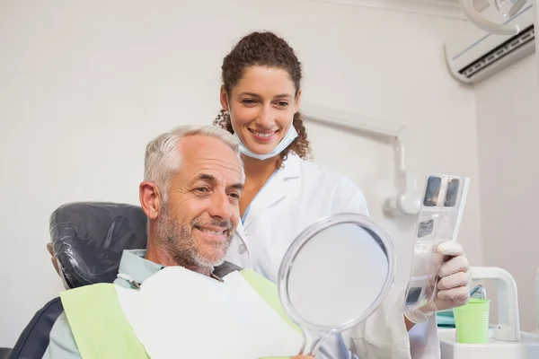 Paciente admirando seu novo sorriso no espelho — Fotografia de Stock