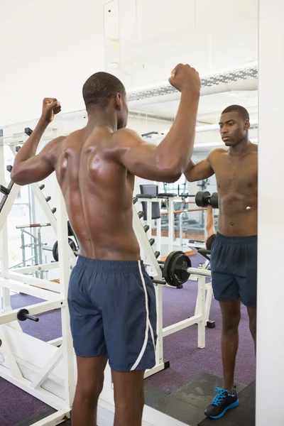 Musculoso hombre flexionando los músculos en el gimnasio — Foto de Stock