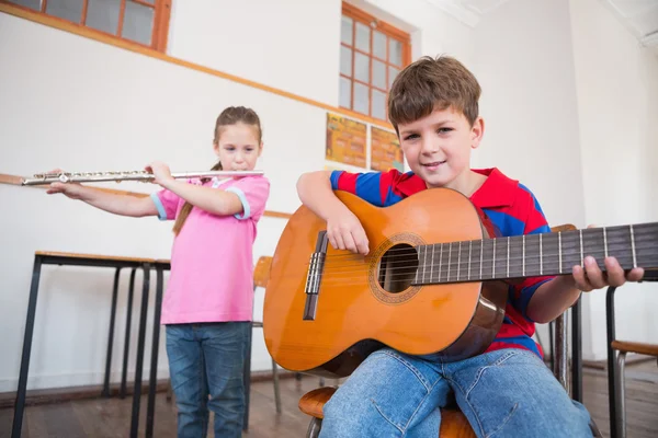 Pupils playing flute and guitar in classroom — Stock Photo, Image