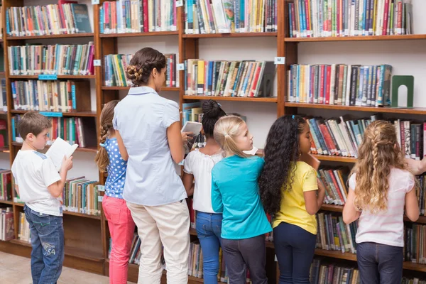 Alunos e professor à procura de livros na biblioteca — Fotografia de Stock