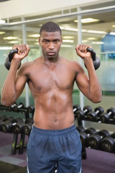 Muscular man lifting kettle bells — Stock Photo, Image