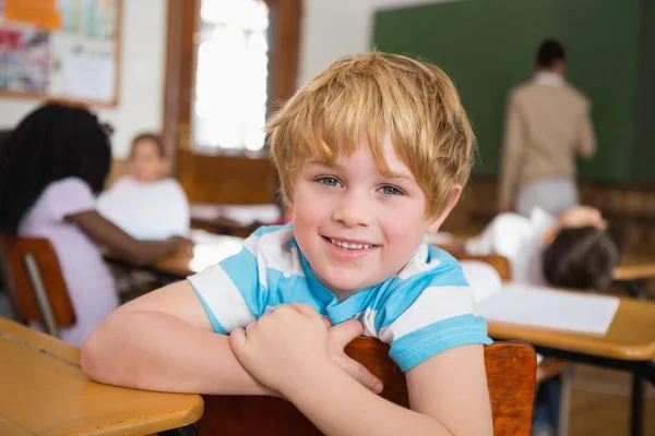 Uśmiechający się uczeń siedział przy biurku — Zdjęcie stockowe