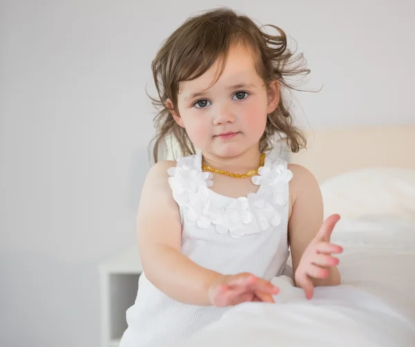 Sevimli küçük kız yatakta oturmuş portre — Stok fotoğraf